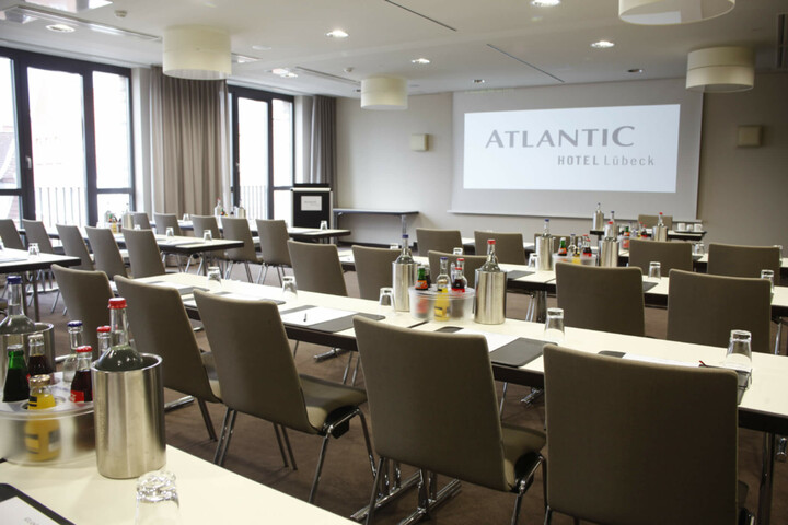 Modern conference room at the ATLANTIC Hotel Lübeck with tables, chairs and drinks, ready for meetings.