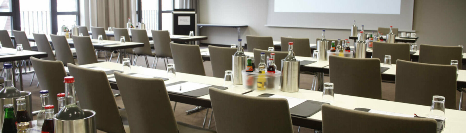 Modern conference room at the ATLANTIC Hotel Lübeck with tables, chairs and drinks, ready for meetings.