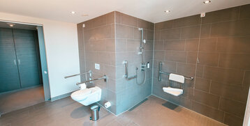 WC mit Haltegriffen und große Dusche mit Sitz im Bad