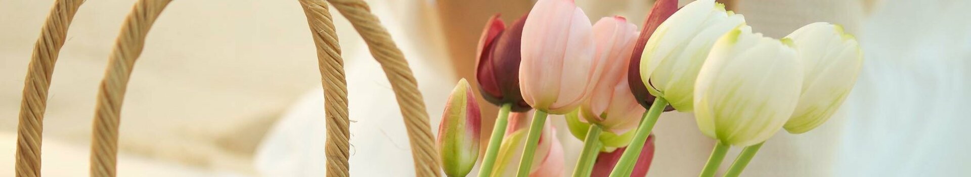 A basket of colorful tulips stands on a picnic blanket on the beach.