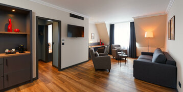 Helles Hotelzimmer mit Sofa, Sesseln, Schreibtisch, TV und modernem Dekor im ATLANTIC Hotel Landgut Horn Bremen.