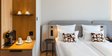 A bed in a Superior Double Room and the coffee station with its warm wooden tones.