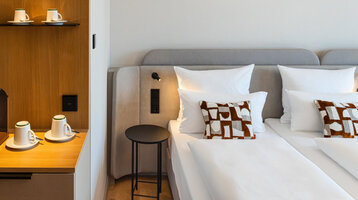 A bed in a Superior Double Room and the coffee station with its warm wooden tones.