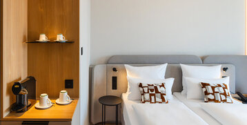 Bett im Superior Doppelzimmer und die Kaffeestation mit warmen Holztönen.