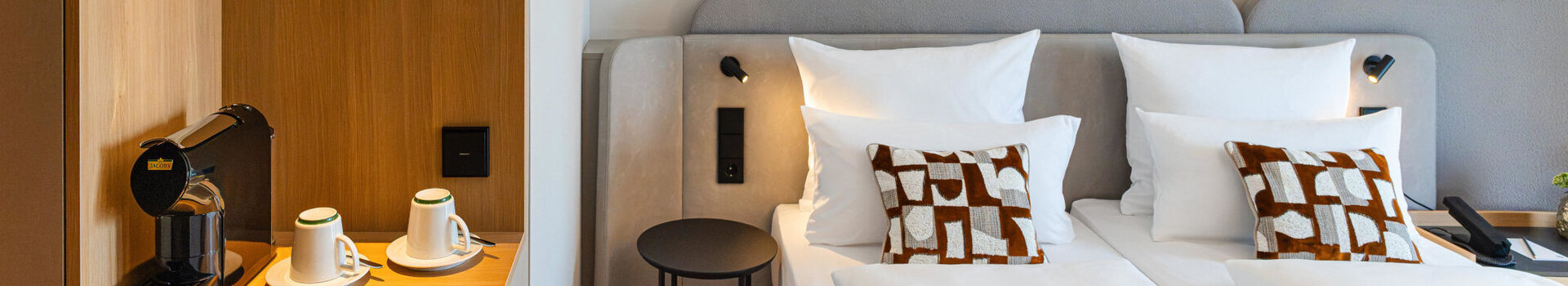 A bed in a Superior Double Room and the coffee station with its warm wooden tones.