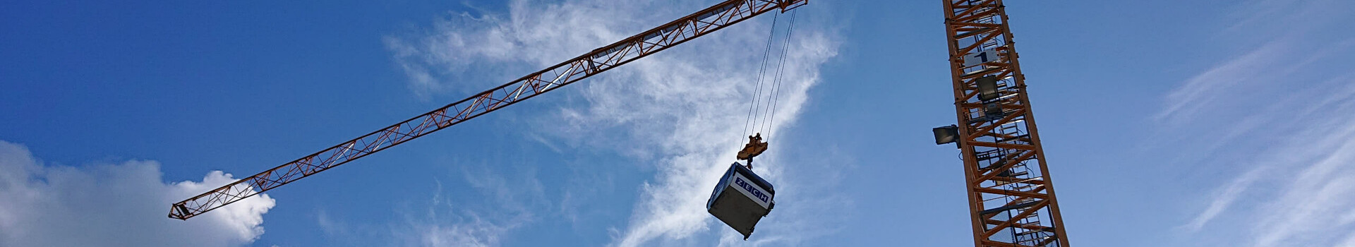 ATLANTIC Hotels lädt ein zum „Tag der Gondel“ in Münster Kran hebt Container vor blauem Himmel mit Wolken.