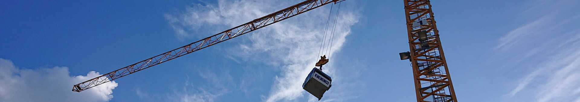 ATLANTIC Hotels lädt ein zum „Tag der Gondel“ in Münster Crane lifts container in front of blue sky with clouds.