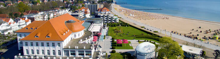 ATLANTIC Grand Hotel Travemünde - Luftaufnahme Luftaufnahme des ATLANTIC Grand Hotel Travemünde mit Strandzugang und Meerblick an einem sonnigen Tag.