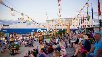 Personen an der festlich geschmückten Promenade von Travemünde, Finnline Fähre im Hintegrund