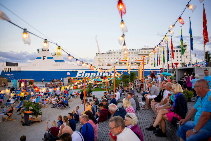 Personen an der festlich geschmückten Promenade von Travemünde, Finnline Fähre im Hintegrund