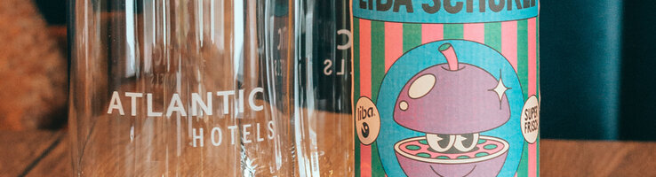 Eine gelbe Flasche LIBA Schorle steht neben einem Glas auf dem "ATLANTIC Hotel Münster" steht.
