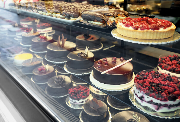 Showcase with a selection of cakes and pastries, including chocolate and berry cakes at the ATLANTIC Grand Hotel Travemünde.