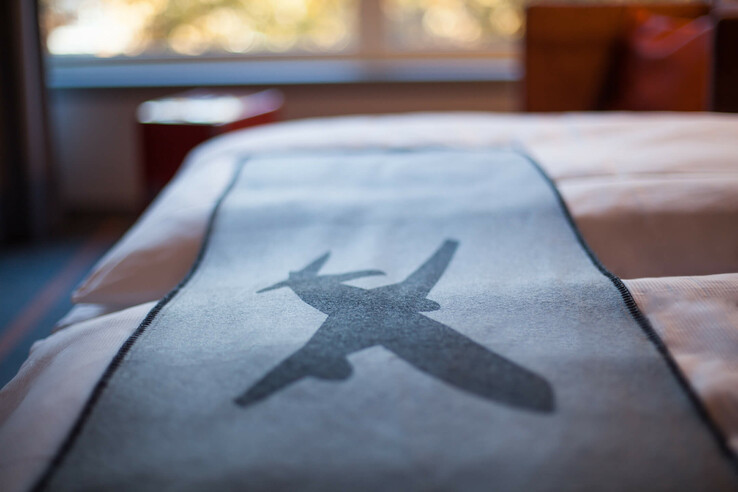 Bedspread in the ATLANTIC Hotel Airport Bremen with airplane motif, blurred window view in the background.