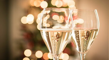 Zwei Sektgläser vor unscharfen, festlichen Lichtern.