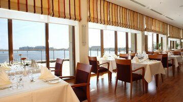 Interior view of the Restaurant Harbour View with set tables in the ATLANTIC Hotel Wilhelmshaven 