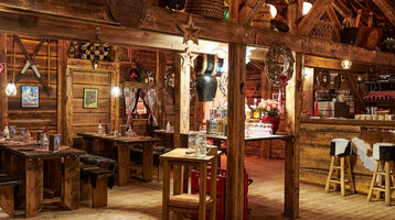 Rustikales Restaurant im ATLANTIC Grand Hotel Bremen mit Holzmöbeln, gemütlicher Beleuchtung und dekorativen Elementen.