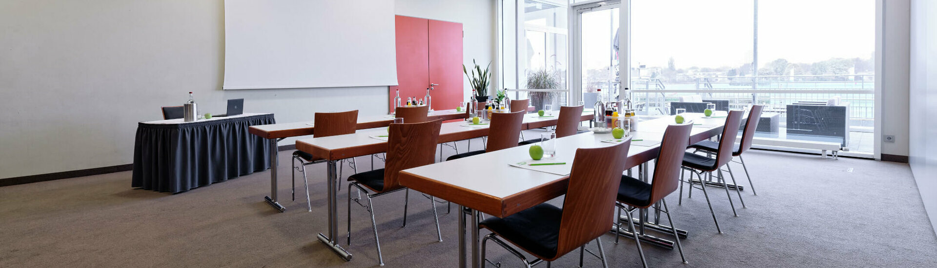 Function room Cheltenham – parliamentary seating Modern conference room with tables, chairs and projector at the ATLANTIC Hotel Galopprennbahn Bremen.