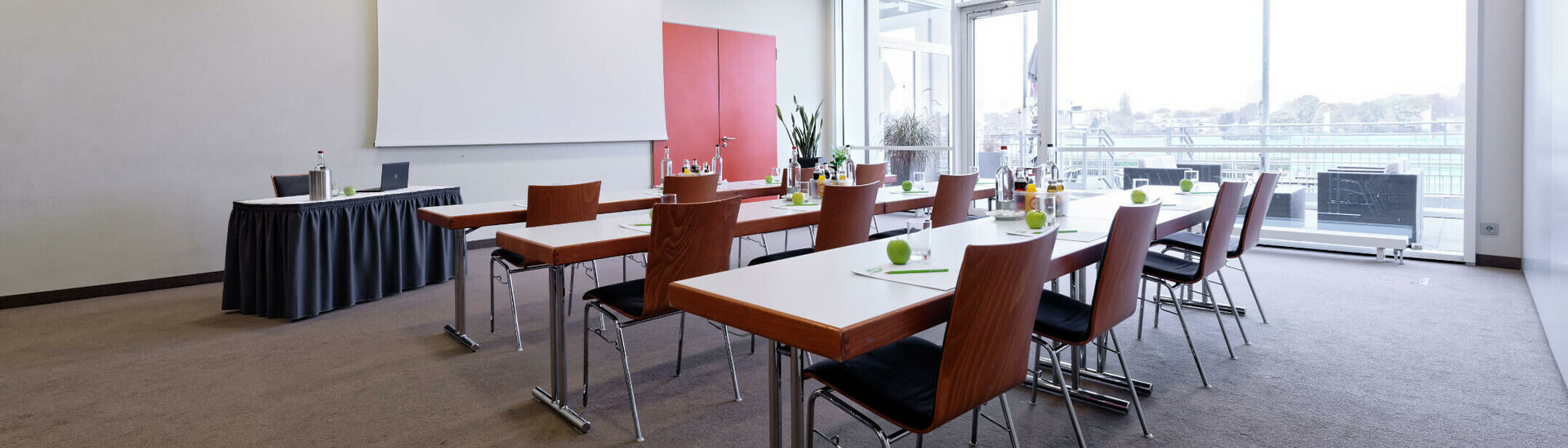 Moderner Konferenzraum mit Tischen, Stühlen und Projektor im ATLANTIC Hotel Galopprennbahn Bremen.