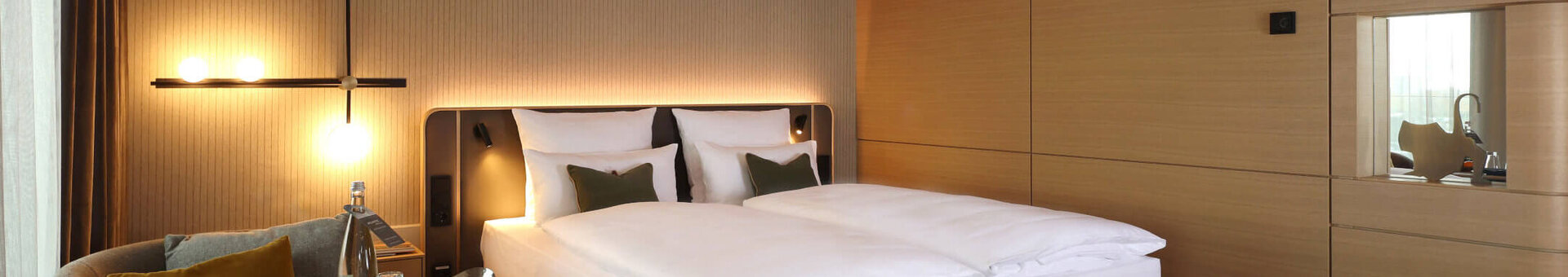 Deluxe Zimmer im ATLANTIC Hotel Heidelberg Modernes Hotelzimmer mit Doppelbett, Sessel, Tisch und stilvoller Beleuchtung im ATLANTIC Hotel Heidelberg.