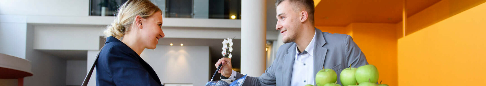 Frau an der Rezeption des ATLANTIC Hotel Universum, Bremen, im Gespräch mit einem Mitarbeiter.