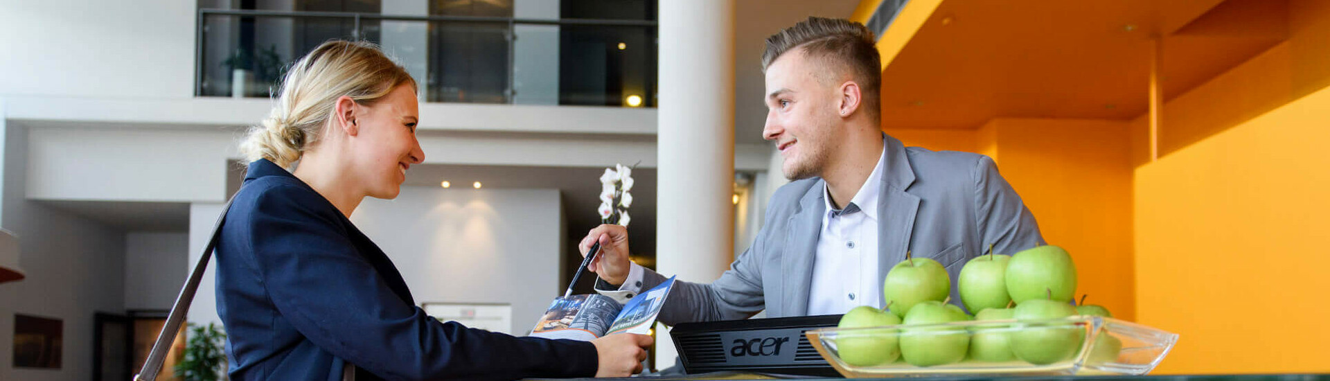 Frau an der Rezeption des ATLANTIC Hotel Universum, Bremen, im Gespräch mit einem Mitarbeiter.