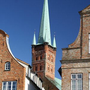 Brick gabled houses and church tower against a blue sky in Lübeck.