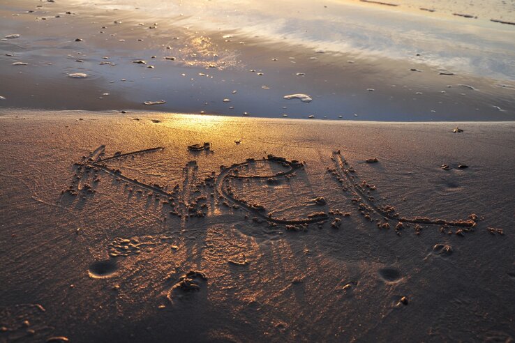 "Keel" in the sand on the beach, illuminated by a golden sunset.