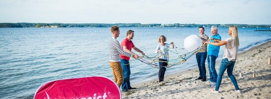 People play a team game on the beach, near the ATLANTIC Grand Hotel Travemünde, with a "teamgeist.com" banner.