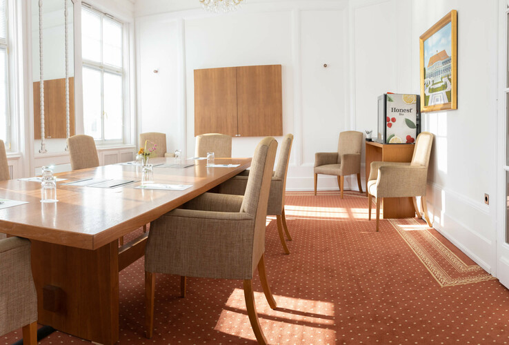 Heller Konferenzraum mit Holztisch, beigen Stühlen, Teppichboden und Tageslicht im ATLANTIC Grand Hotel Travemünde.