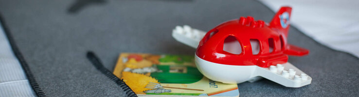 ATLANTIC Hotel Airport Bremen Family Special Toy airplane and children's book on a grey bedspread at the ATLANTIC Hotel Airport Bremen.