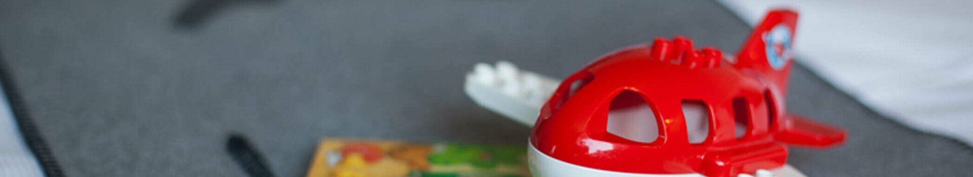 ATLANTIC Hotel Airport Bremen Family Special Toy airplane and children's book on a grey bedspread at the ATLANTIC Hotel Airport Bremen.