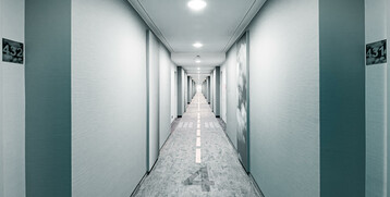 Heller Hotelgang mit Teppich im Flugbahn-Design, Türen links und rechts, ATLANTIC Hotel Airport Bremen.