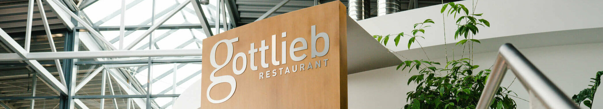 Restaurant gottlieb Bremen Eingang Modernes Restaurant mit Holzverkleidung, Glasdach und Pflanzen im Innenbereich.