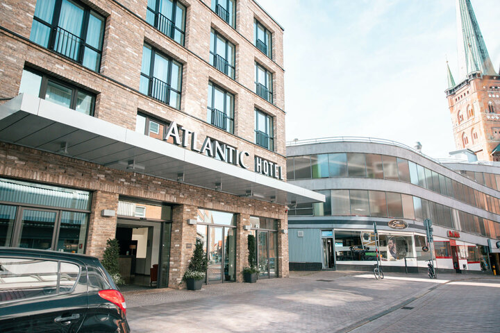 ATLANTIC Hotel Lübeck Hoteleingang Aussenansicht mit Kirche im Hintegrund