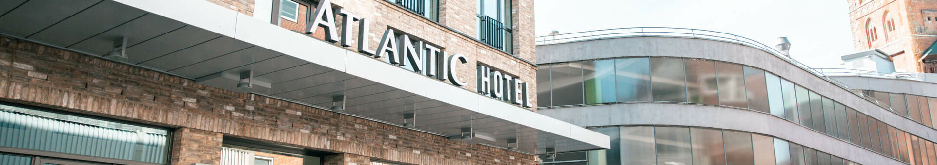 ATLANTIC Hotel Lübeck Hoteleingang Aussenansicht ATLANTIC Hotel Lübeck Hoteleingang Aussenansicht mit Kirche im Hintegrund