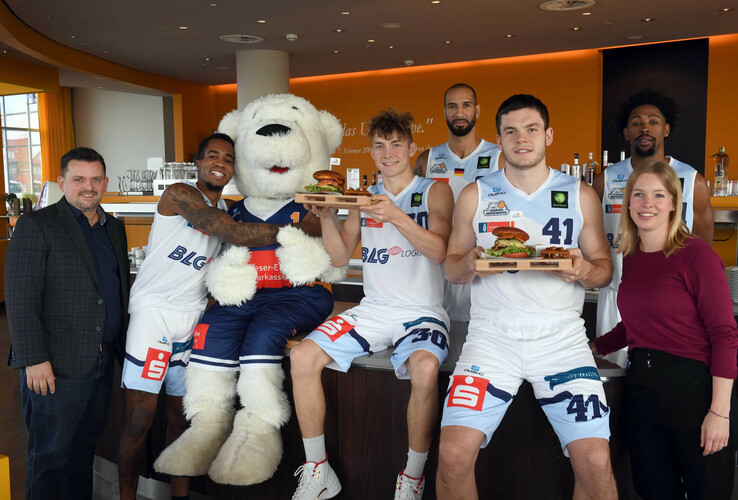 Basketball players pose with mascots and burgers at the ATLANTIC Hotel Sail City, Bremerhaven.