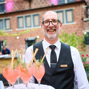 Lächelnder Kellner mit Getränken im Hofgartes des ATLANTIC Grand Hotel Bremen