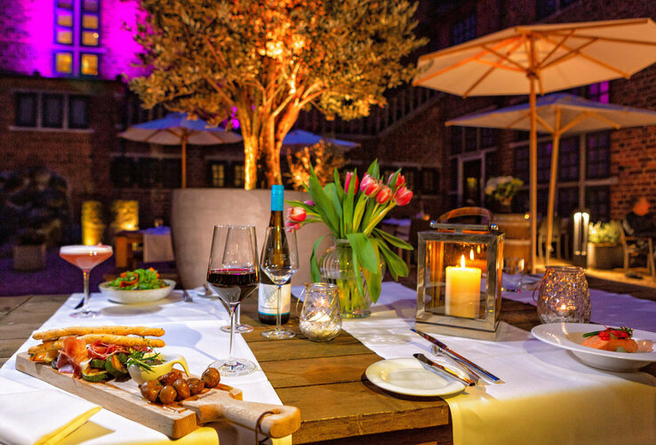 Elegant outdoor dinner with candlelight, wine and flowers on a terrace of the ATLANTIC Grand Hotel Bremen.