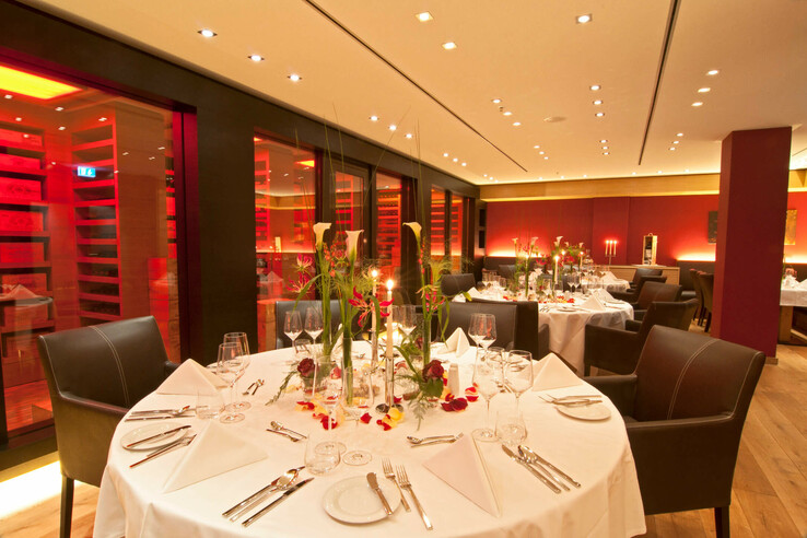 Elegant restaurant in the ATLANTIC Hotel Kiel with stylishly laid tables, candlelight and modern, warm lighting.