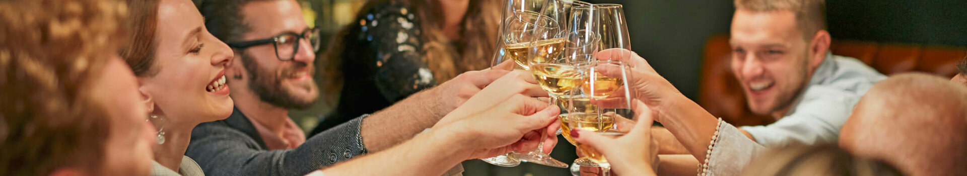 ATLANTIC Hotel Münster Dining & Drinks A group of people toast cheerfully with wine glasses at a laid table.