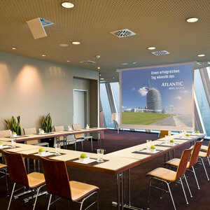Modern conference room in the ATLANTIC Hotel Sail City with U-shaped seating and screen, view of Bremerhaven.