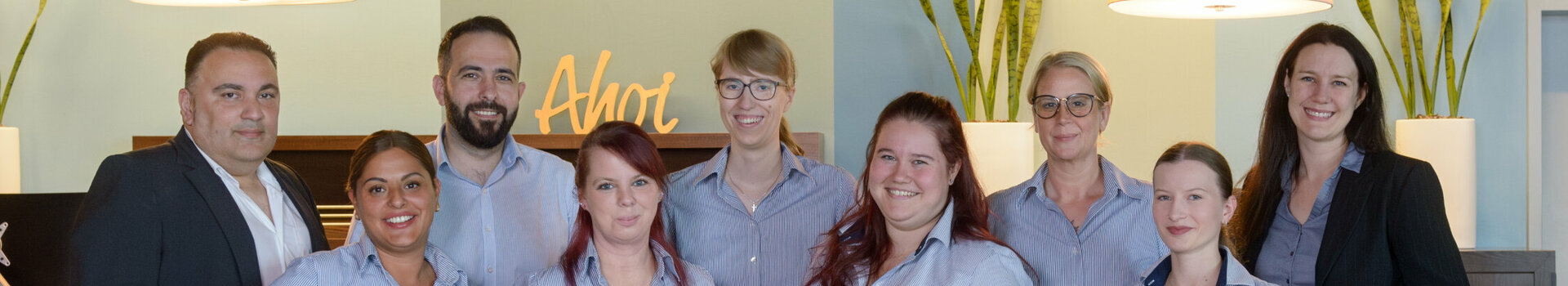 The team at the ATLANTIC Hotel Sail City smiles friendly at reception.