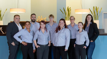 Das Team des ATLANTIC Hotel Sail City lächelt freundlich an der Rezeption.