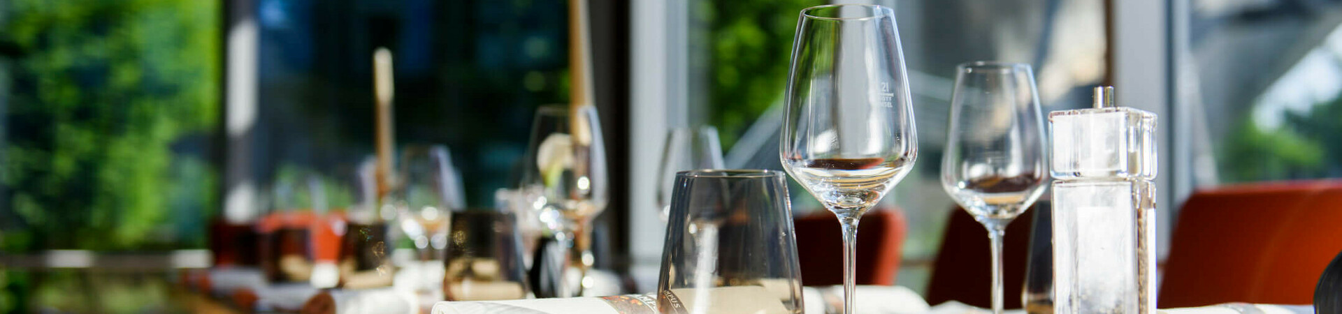 Eleganter, sonnendurchfluteter Restauranttisch im ATLANTIC Hotel Universum, gedeckt mit Gläsern und Servietten.