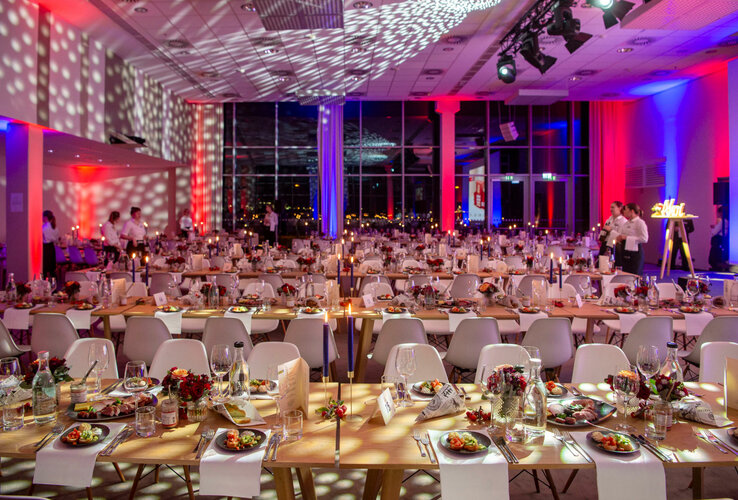Festlich gedeckter Bankettsaal im ATLANTIC Hotel Sail City, Bremerhaven, mit Kerzenlicht und bunten Lichteffekten.