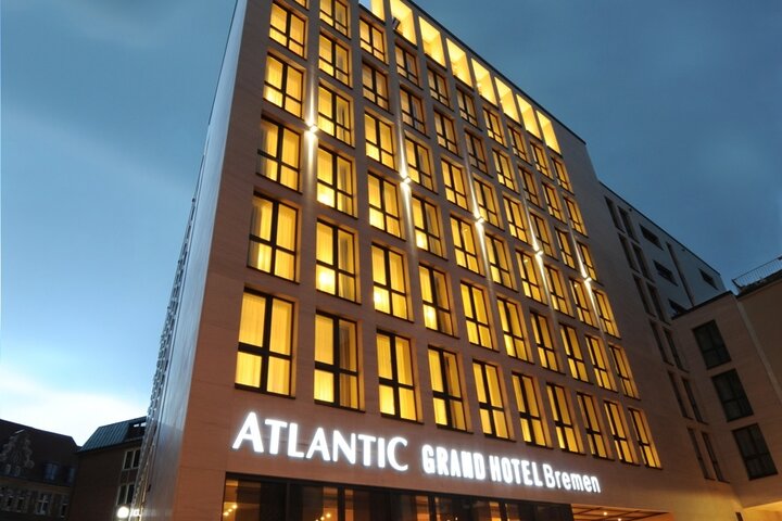 Exterior view of the ATLANTIC Grand Hotel in Bremen at twilight Modern hotel building at dusk, with illuminated windows and the lettering "ATLANTIC Grand Hotel Bremen".