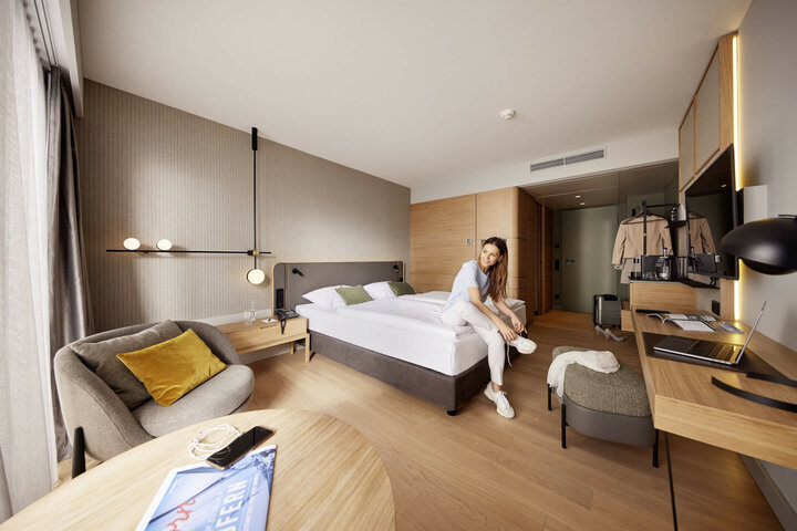 Modernes Hotelzimmer mit Doppelbett, Sitzbereich, Schreibtisch und stilvoller Beleuchtung im ATLANTIC Hotel Heidelberg.