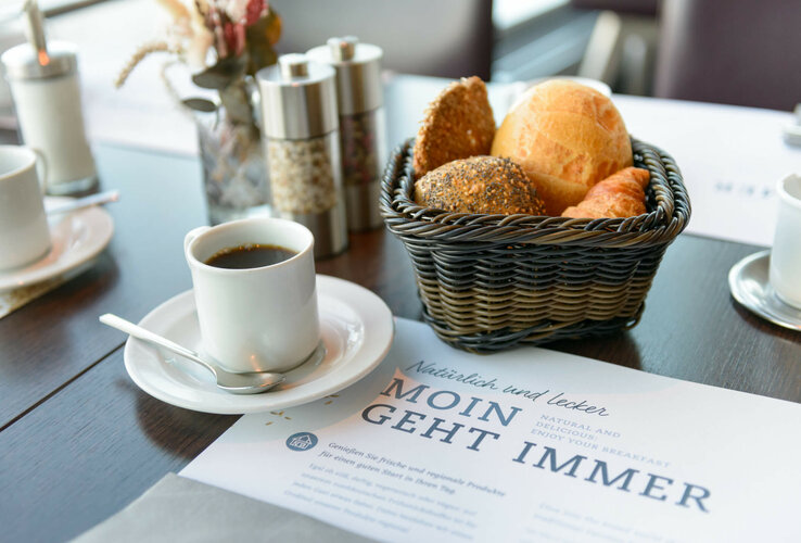 Breakfast table with coffee, bread basket and spices at the ATLANTIC Hotel Sail City, Bremerhaven.