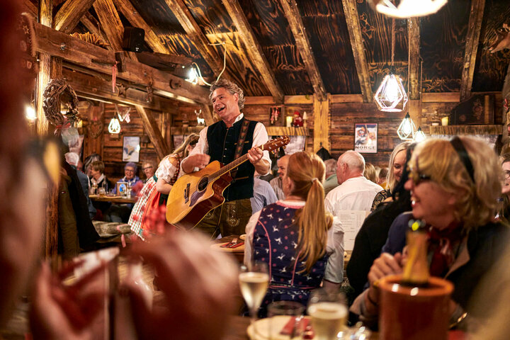 The Hamburg Lopes Duo heated up the atmosphere in the Almhütte. Cozy, rustic atmosphere with a musician playing the guitar and guests in traditional dress celebrating.