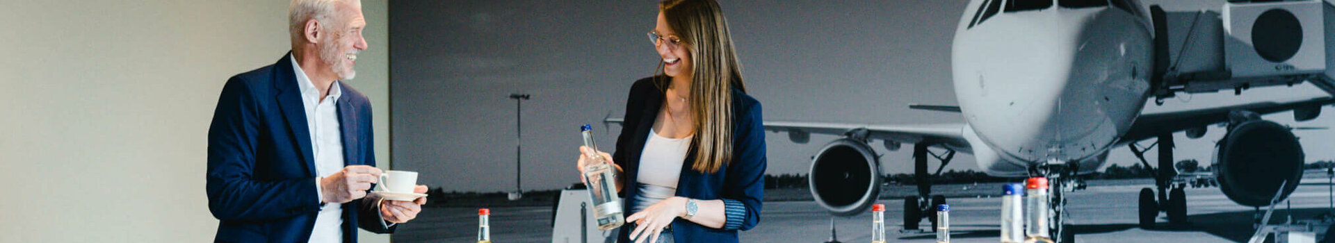 Two people in a conference room at the ATLANTIC Hotel Airport Bremen, with a picture of an airplane in the background.